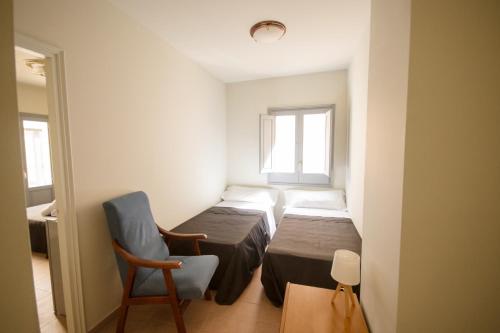 a small room with two beds and a chair at Center Plaza Figueres in Figueres