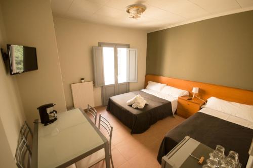 a hotel room with two beds and a table at Center Plaza Figueres in Figueres