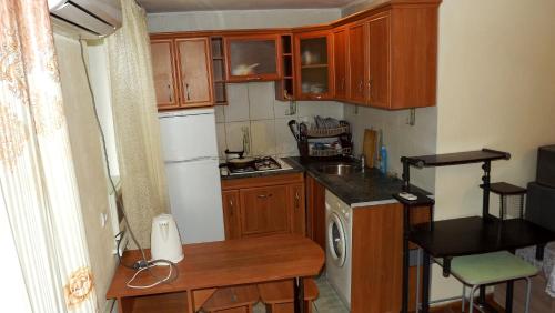 a small kitchen with wooden cabinets and a sink at Apartments on Logvinenko 26a in Bishkek