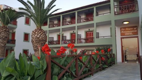 un edificio con palmeras y flores delante de él en The Flower Of Monemvasia Hotel, en Monemvasia