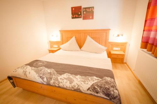 a bedroom with a bed with white sheets and two tables at Bodenhof Ferienwohnungen in Fieberbrunn