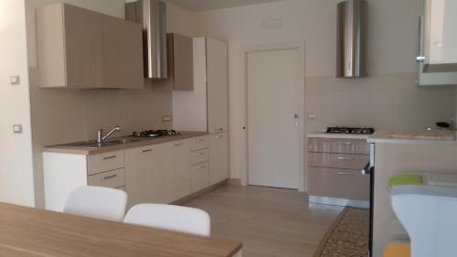 a kitchen with white cabinets and a sink and a table at Affittacamere Rubino Guest House in Ponte nellʼAlpi