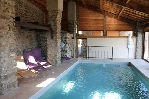 a swimming pool in a room with a stone building at Domaine de Chabanet in Privas