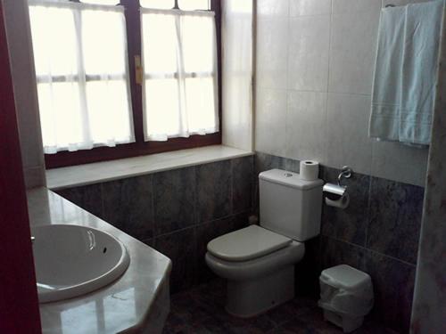 a bathroom with a white toilet and a sink at Posada Playa de Langre in Langre