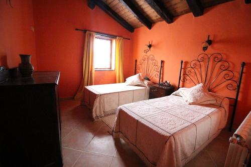 a bedroom with two beds and an orange wall at Posada de Bielva in Bielva