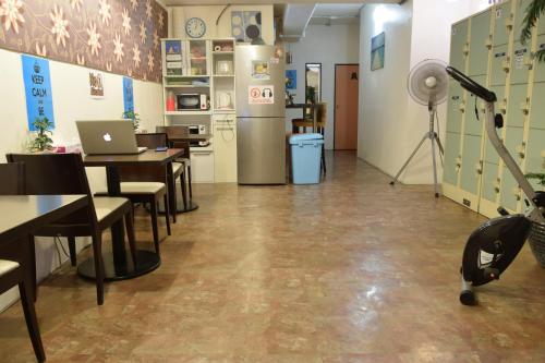a room with tables and chairs and a refrigerator at Kumoji-so Hostel in Naha