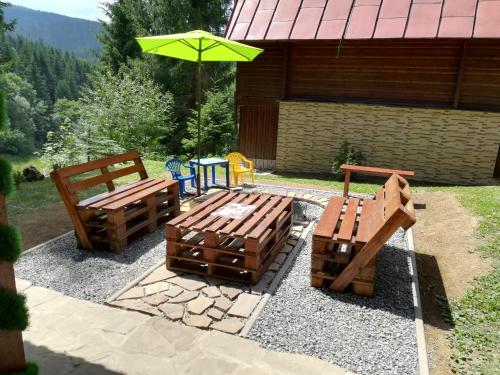 two wooden benches and an umbrella on a patio at Chata Safran in Donovaly