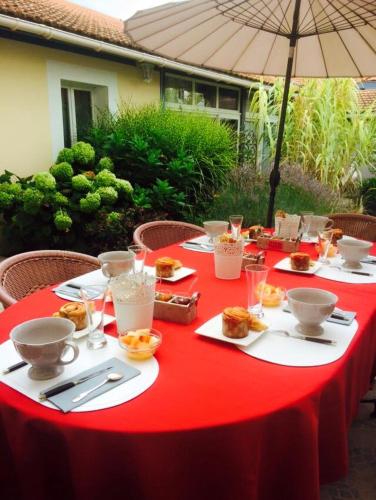 une table rouge avec de la nourriture et un parapluie dans l'établissement La Maison de Lilly, à Arcachon