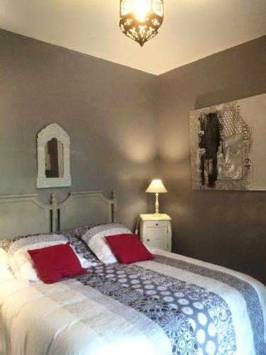une chambre avec un grand lit avec deux oreillers rouges dans l'établissement La Maison de Lilly, à Arcachon
