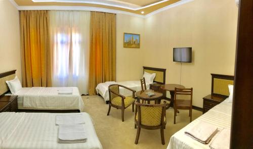 a hotel room with two beds and a table at Muzaffar Hotel Samarkand in Samarkand