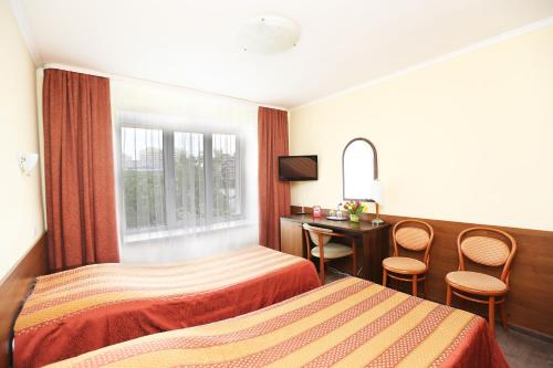 Habitación de hotel con 2 camas, escritorio y ventana en Sputnik Hotel, en Minsk