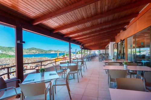 a restaurant with tables and chairs with a view of the ocean at FERGUS Club Carema Splash in Fornells