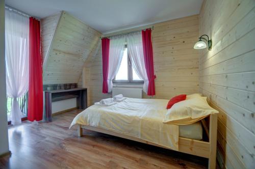ザコパネにあるApartamenty Gawlaki Zakopaneの木製の壁と赤いカーテン付きのベッドが備わるベッドルーム1室が備わります。