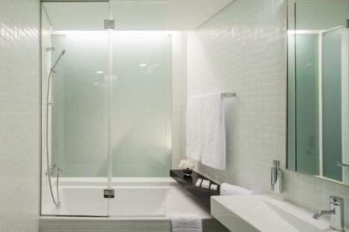 a bathroom with a shower and a tub and a sink at Hotel 3K Europa in Lisbon