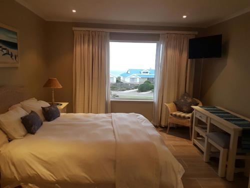 a bedroom with a bed and a desk and a window at Pinnacle Point Lodge 81 in Mossel Bay