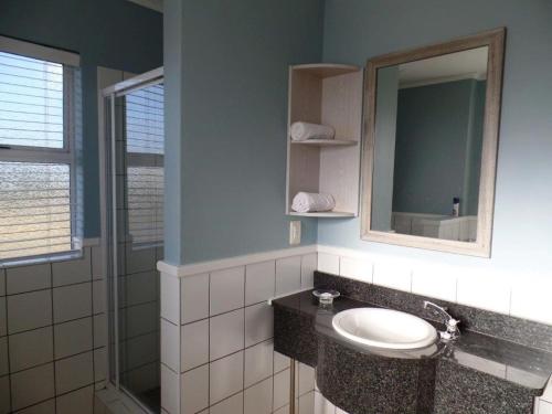 a bathroom with a sink and a mirror and a shower at Pinnacle Point Lodge 81 in Mossel Bay