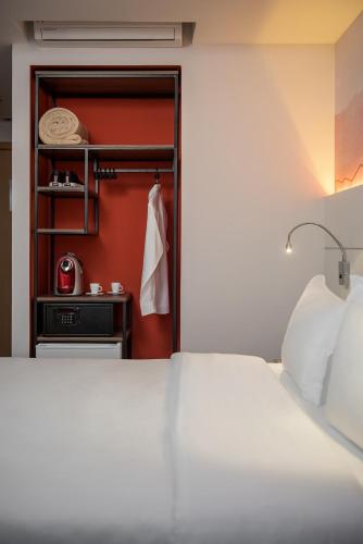 a bedroom with a white bed and a red wall at Intercity Porto Alegre Cidade Baixa in Porto Alegre
