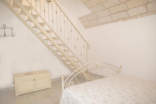 a white room with a bed and a staircase at Sottacastieddu in Avetrana