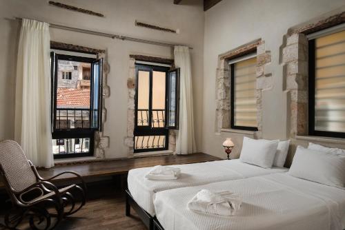 a bedroom with two beds and a chair and windows at Nonnalena Boutique Hotel in Chania