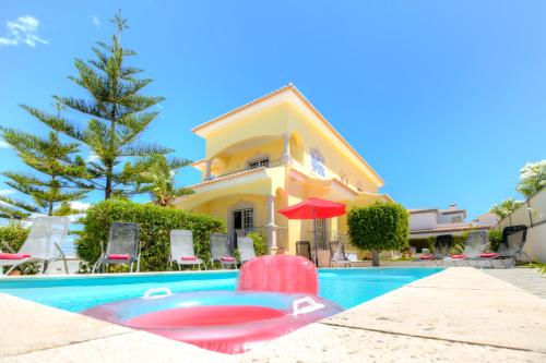 a villa with a swimming pool in front of a house at Villa Menir in Lagoa