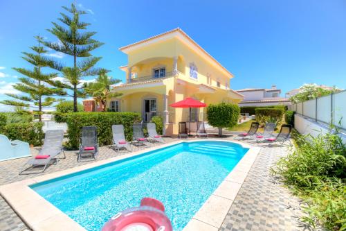 a villa with a swimming pool in front of a house at Villa Menir in Lagoa