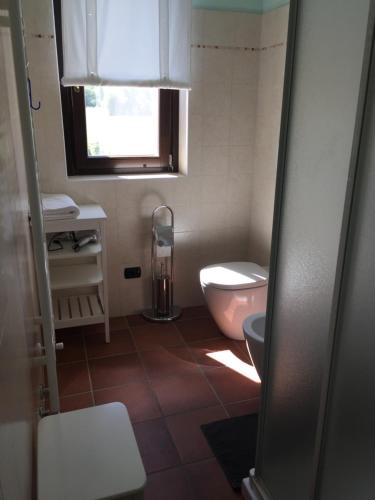 łazienka z różową toaletą i oknem w obiekcie Agriturismo La Farazzina w mieście Oleggio