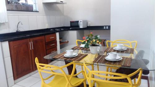 a kitchen with a table and yellow chairs in a kitchen at Apartamentos Ipanema Charme in Itacaré