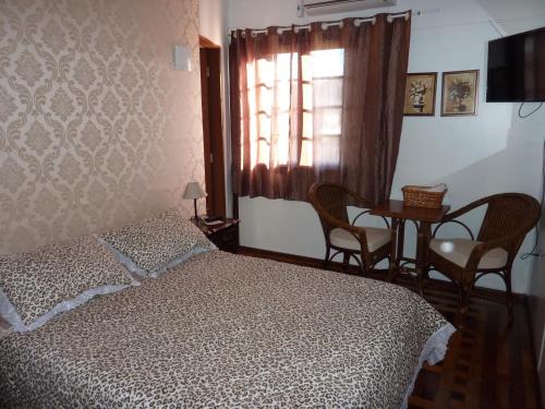 1 dormitorio con cama, mesa y ventana en Pousada Casa Amarela, en Canela