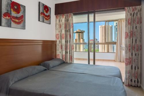 a bedroom with a bed and a large window at Gemelos 4 - Beninter All Inclusive in Benidorm