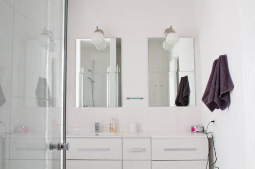 a white bathroom with a shower and two mirrors at Minihotel Graz in Graz