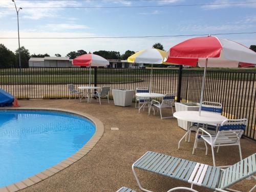 a patio with tables and umbrellas and a pool at Travel Inn & Suites in Atlanta