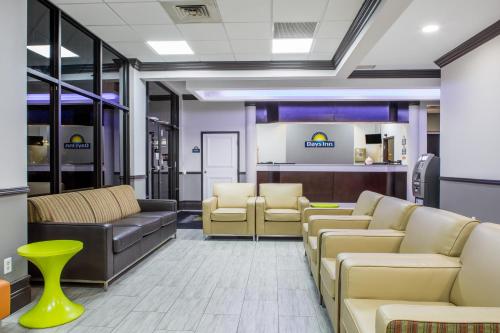 a waiting area with couches and chairs in a waiting room at Days Inn & Suites by Wyndham Orlando Airport in Orlando