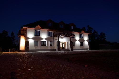 a large white house with lights on it at night at Dworek Zyskowskiego in Danowskie