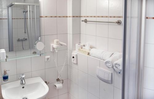 a white bathroom with a sink and a shower at Hotel Jess am Meer in Büsum