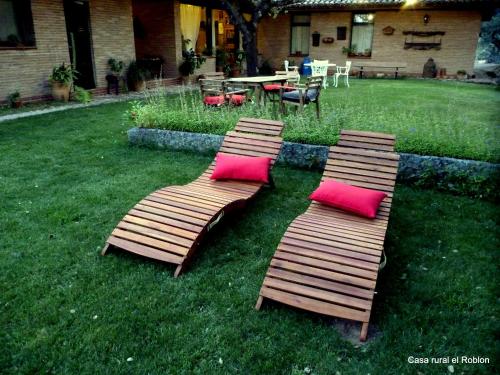 three wooden benches with pink pillows on a yard at Casa Rural El Roblon in Sartajada