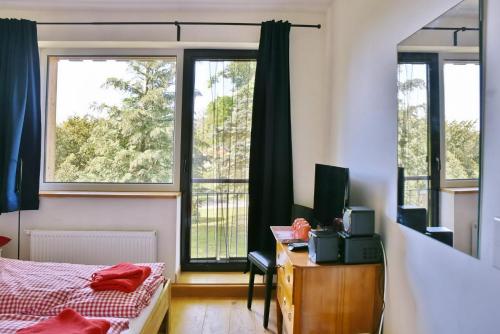 a bedroom with a bed and a desk and two windows at Seehaus Hartwigsdorf in Klein Vielen