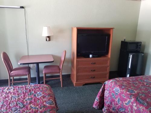 Habitación de hotel con TV, mesa y sillas en Haltom Inn Fort Worth, en Fort Worth