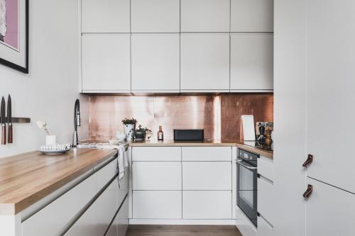 a kitchen with white cabinets and a wooden counter top at Neumannsgate 4 in Bergen