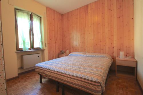 アウロンツォ・ディ・カドーレにあるAppartamento Panorama Dolomitiの木製の壁のベッドルーム1室(ベッド1台付)