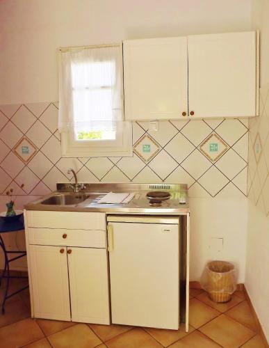a kitchen with white cabinets and a sink and a window at Votsalo Apartments in Naousa