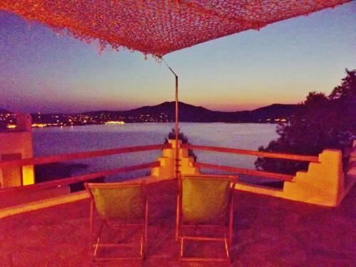 a table and chairs sitting on a deck with a view of the water at Votsalo Apartments in Naousa