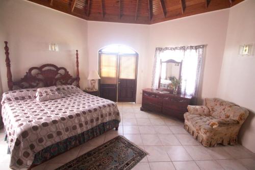 a bedroom with a bed and a chair and a mirror at Sea View Chateau in Montego Bay