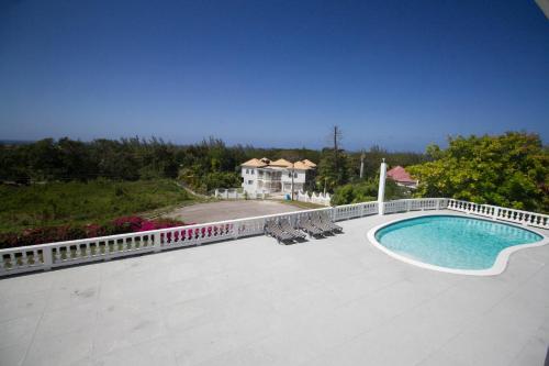 a large pool with chairs and a fence and a house at Sea View Chateau in Montego Bay