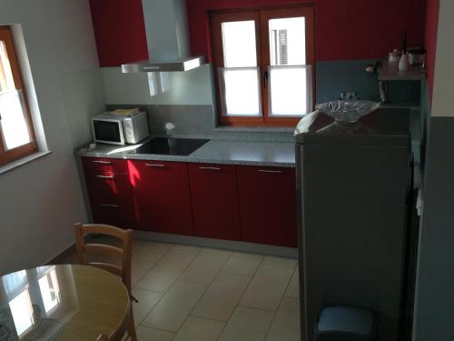 a kitchen with red cabinets and a sink and a table at Hiša Kranjc in Kobarid