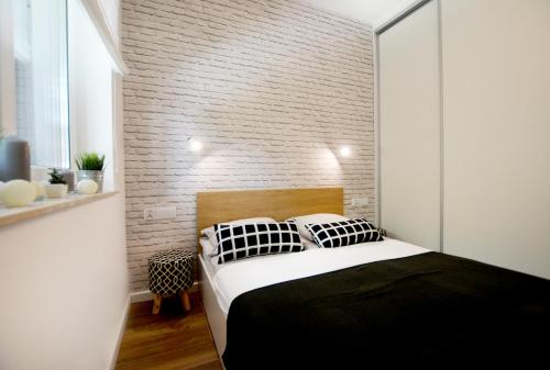 a bedroom with a bed and a brick wall at Apartament 27 Dwie Sosny in Ustronie Morskie