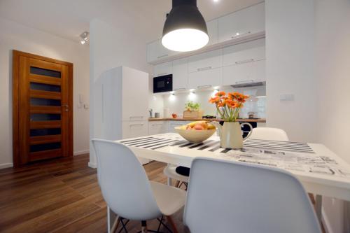 a white kitchen with a table and chairs at Apartament 27 Dwie Sosny in Ustronie Morskie
