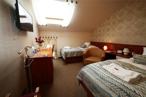 a hotel room with two beds and a chair at Hotel Roudna in Plzeň