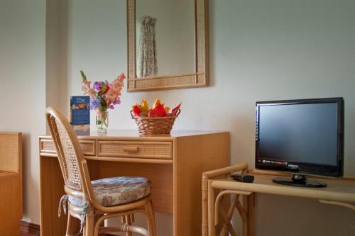 a living room with a tv and a desk with a chair at Alte Hotel in Alte
