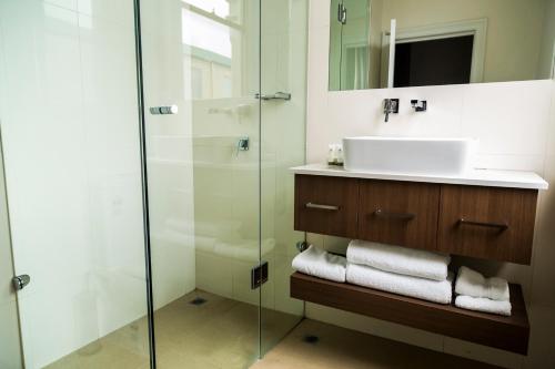 a bathroom with a sink and a glass shower at Simmers Serviced Apartments in Williamstown