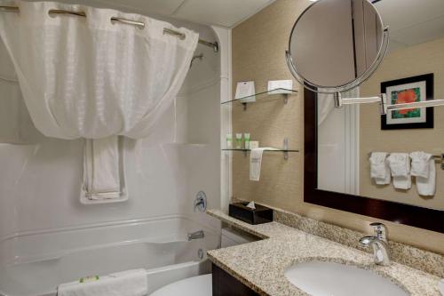 a bathroom with a sink and a mirror and a tub at Best Western PLUS City Centre Inn in Edmonton